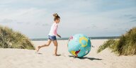Ein Kind mit einem Ball in Globusform.