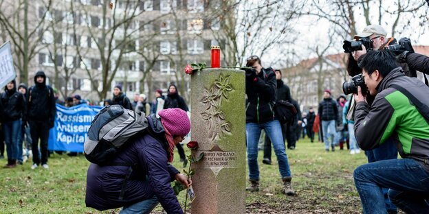 Eine Demonstrantin legt in Dessau 2018 Blumen zum Gedenkstein für Alberto Adriano