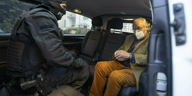 Prinz Reuss sitzt mit Handschellen in einem Polizeifahrzeug