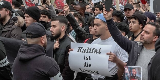 Teilnehmer einer islamistischen Demonstration in Hamburg, einer trägt ein Schild mit der Aufschrift "Kalifat ist die Lösung"