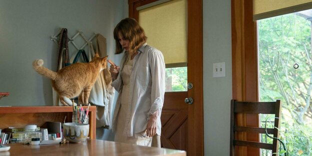 Lizzy (Michelle Williams) steht mit einer Katze in ihrer Wohnung.