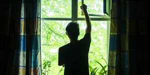 Ein Mann öffnet ein Fenster in seinem Schlafzimmer