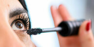 Eine Frau schminkt sich die Augen mit Mascara